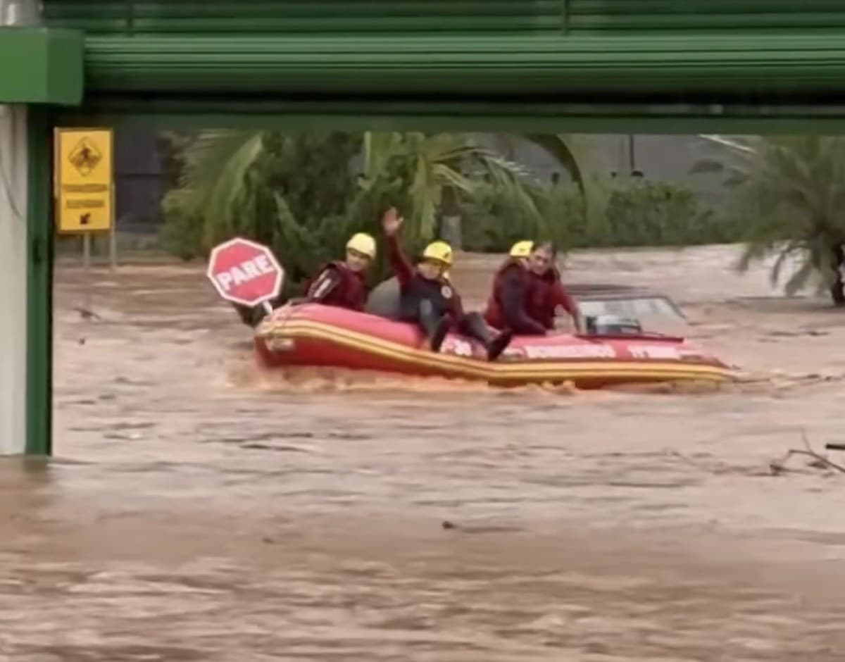 Bombeiros em bote inflável em rua tomada pela água durante resgate em Joaçaba