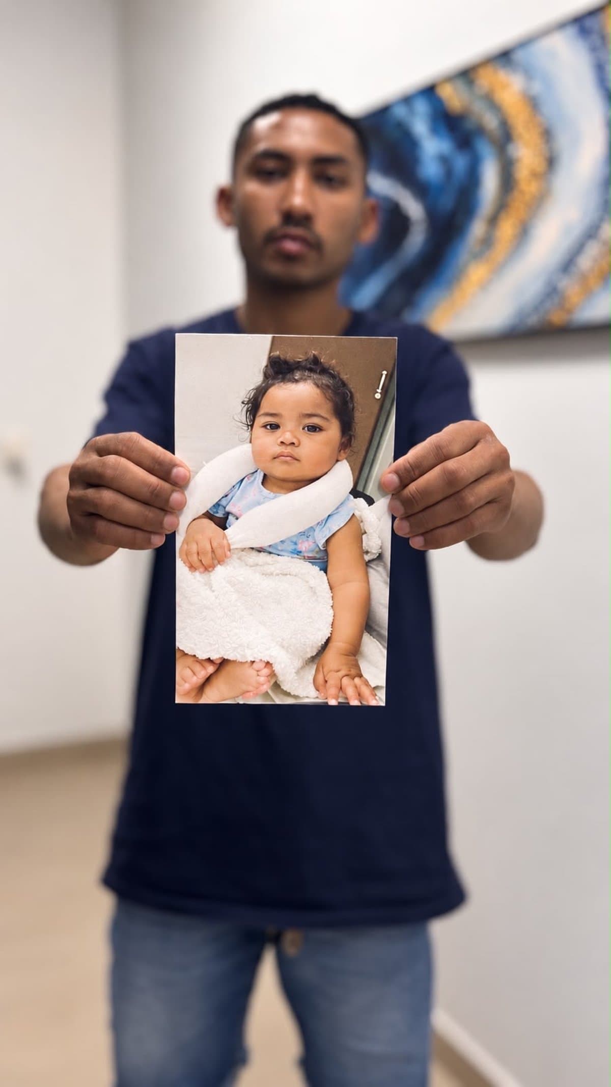 Pai segura foto de Lavínia, de 1 ano e 3 meses